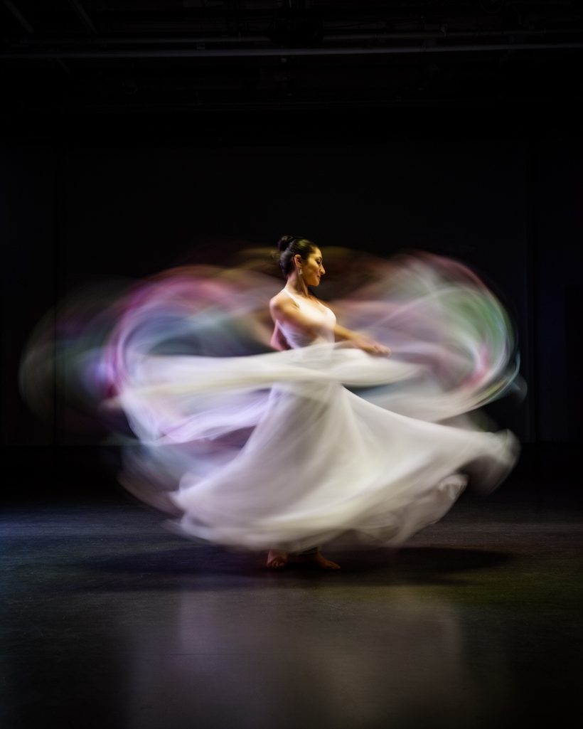Dancer in flowing white fabric surrounded by trails of light